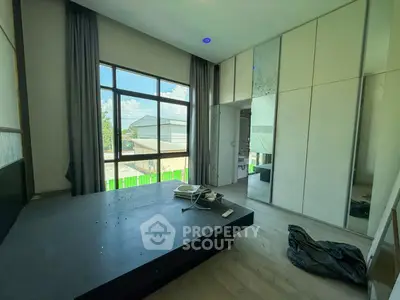 Spacious bedroom with large window and built-in wardrobe, offering natural light and modern design.