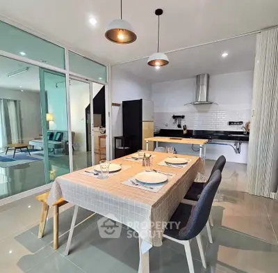 Modern open-layout kitchen and dining area with stylish lighting and glass partition.