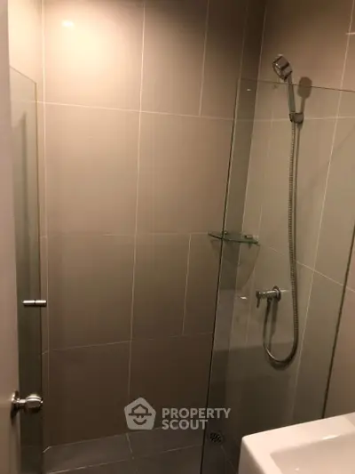 Modern bathroom with sleek glass shower and neutral tiles.