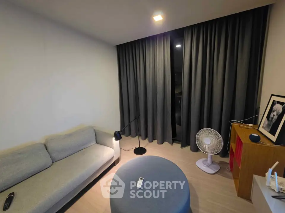 Cozy living room with modern sofa, stylish lighting, and elegant curtains for a comfortable ambiance.