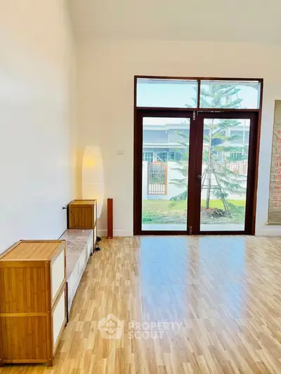 Spacious living room with large windows and wooden flooring, offering a bright and airy atmosphere.