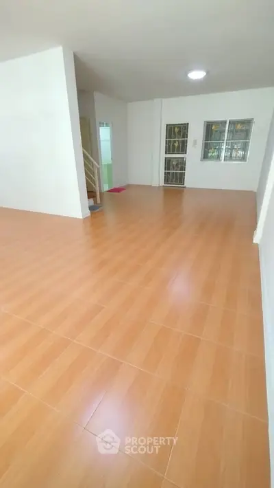 Spacious empty living room with wooden flooring and staircase
