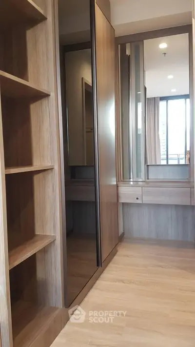 Spacious walk-in closet with wooden shelves and mirrored doors in modern apartment.