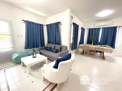 Spacious living room with modern decor and dining area, featuring blue curtains and white furniture.