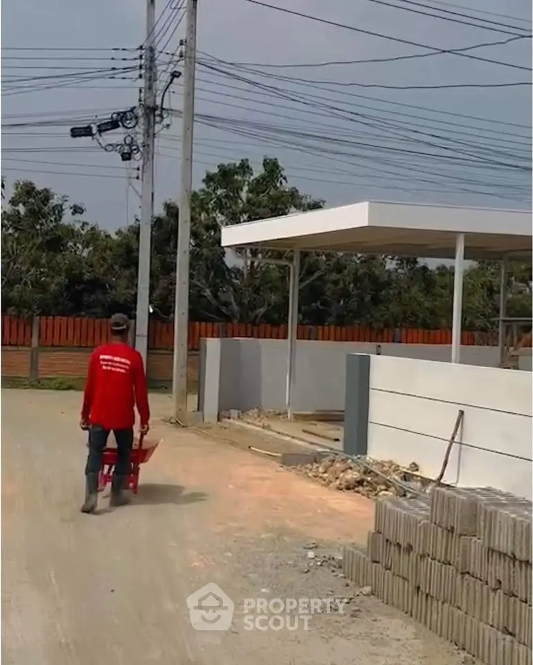 Construction site with worker pushing wheelbarrow near modern building entrance