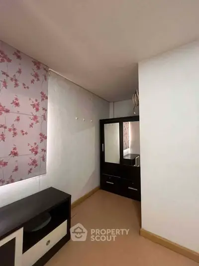 Cozy bedroom with floral curtains and sleek wardrobe, perfect for a tranquil retreat.