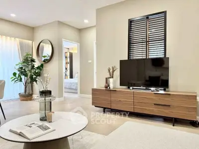 Modern living room with stylish decor, featuring a sleek TV stand, large mirror, and cozy seating area.