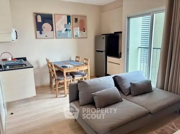 Modern living room with open kitchen and balcony access, featuring stylish decor and natural light.