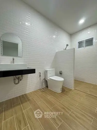 Modern bathroom with sleek design, featuring white tiles and wooden flooring for a contemporary look.