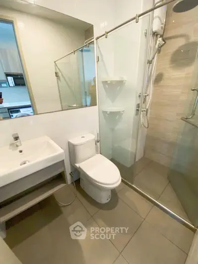 Modern bathroom with glass shower and sleek fixtures in contemporary apartment.