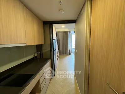 Modern kitchen with sleek cabinetry and open layout leading to a bright living area.