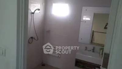 Modern bathroom with shower and sink in a well-lit space.