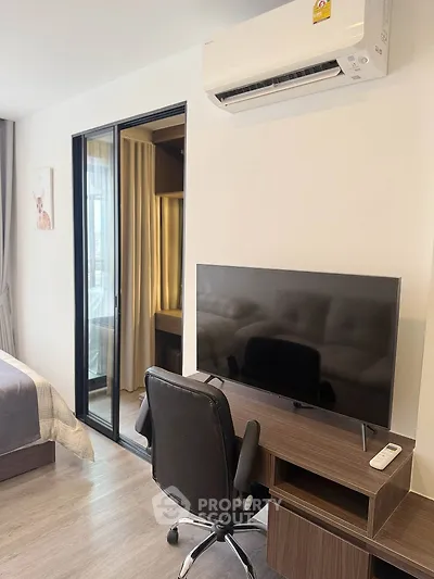 Modern bedroom with sleek desk, TV, and air conditioning, perfect for comfortable living.
