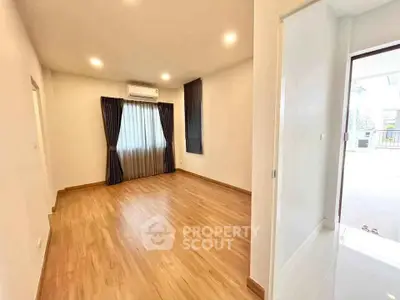 Spacious empty room with wooden flooring and large window, perfect for customization.