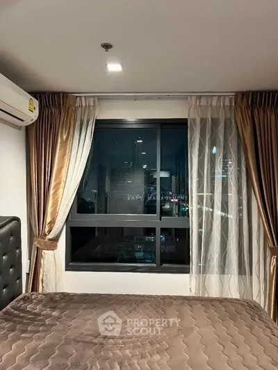 Cozy bedroom with city view, featuring elegant curtains and modern decor.