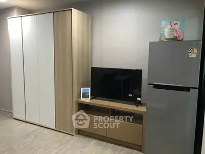 Modern living room with sleek wardrobe, TV stand, and stainless steel fridge.