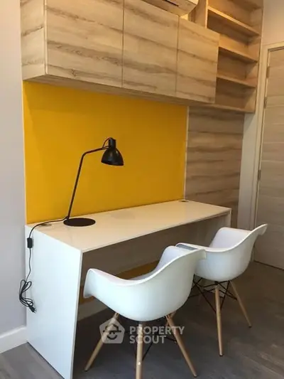 Modern study area with sleek desk and chairs, vibrant yellow accent wall, and stylish wooden cabinets.
