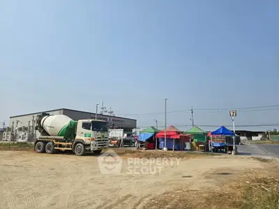 Commercial property with construction truck and colorful tents in open area.