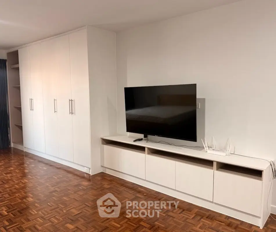 Spacious living room with modern TV setup and elegant parquet flooring
