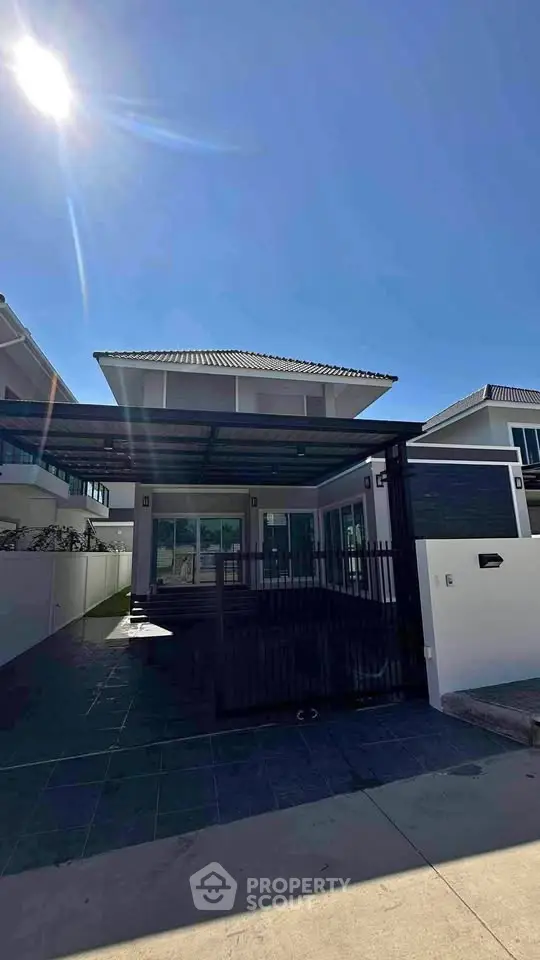 Modern two-story house with sleek design and spacious driveway under clear blue sky.