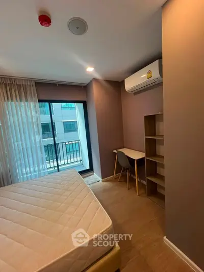 Modern bedroom with balcony access and study area in a stylish apartment.