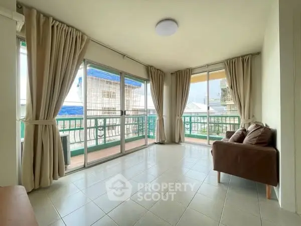 Spacious living room with large windows and balcony access, offering ample natural light.