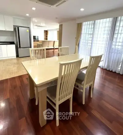 Spacious dining area with elegant wooden flooring and modern kitchen appliances.