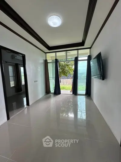 Spacious living room with large window and wall-mounted TV, offering a bright and airy atmosphere.