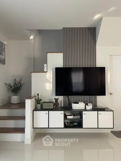 Modern living room with sleek TV setup and stylish staircase