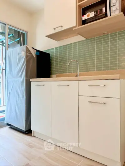Modern kitchen with sleek cabinetry and appliances, featuring a compact fridge and microwave.