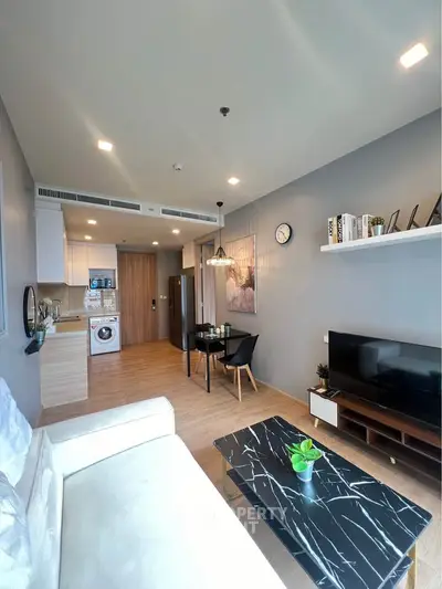 Modern living room with open kitchen, stylish decor, and natural light