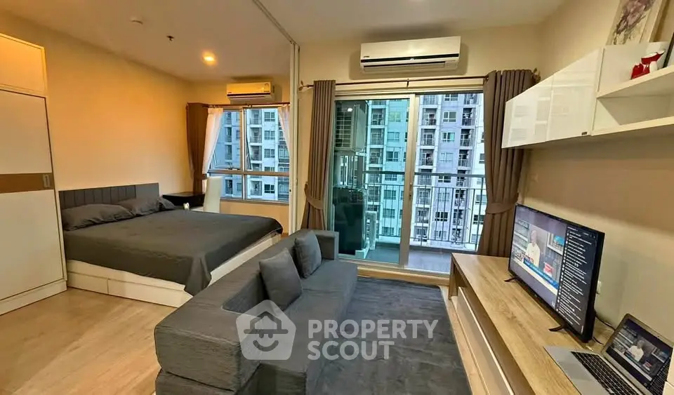 Modern studio apartment with balcony and city view, featuring sleek furniture and open layout.