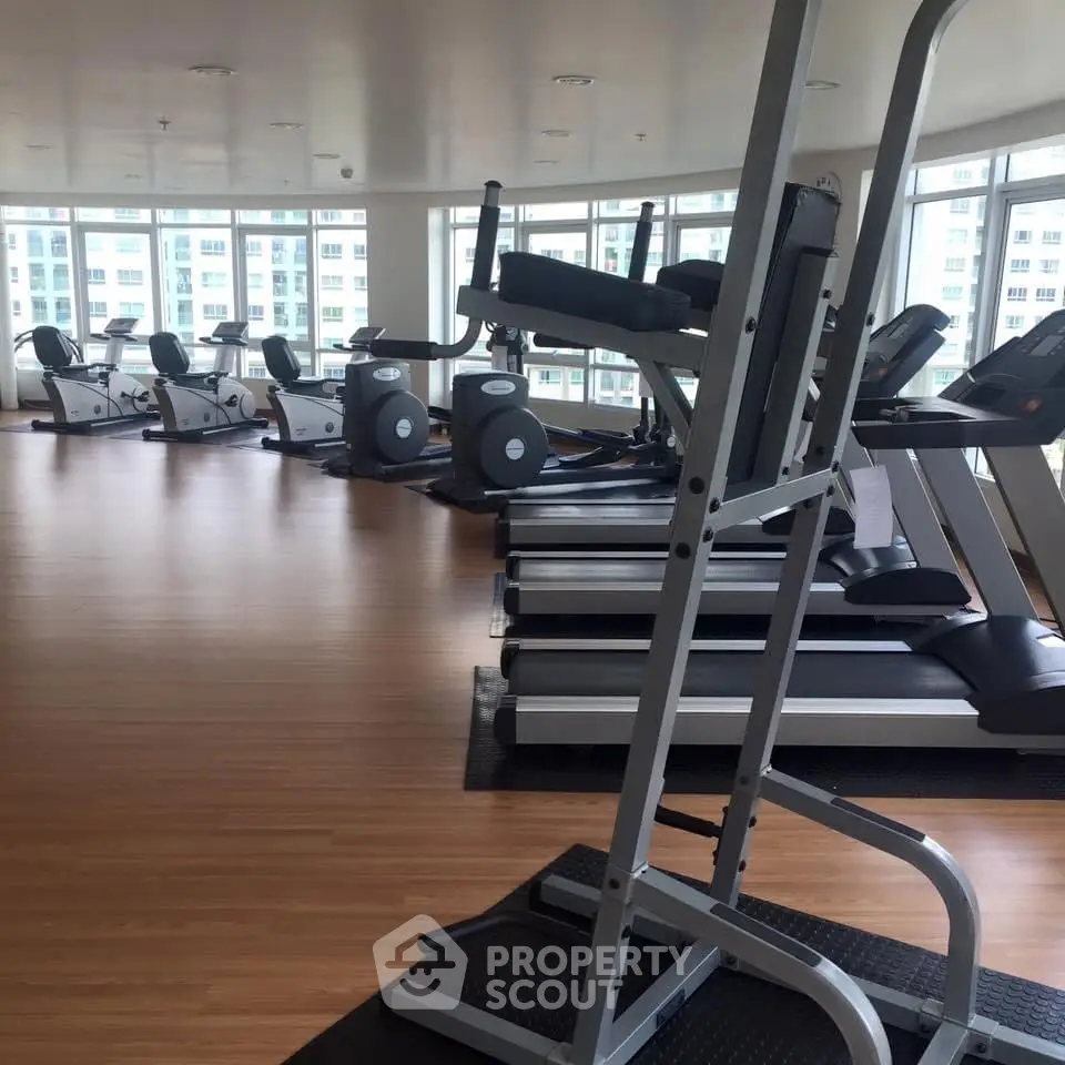 Spacious gym with modern equipment and large windows offering city views