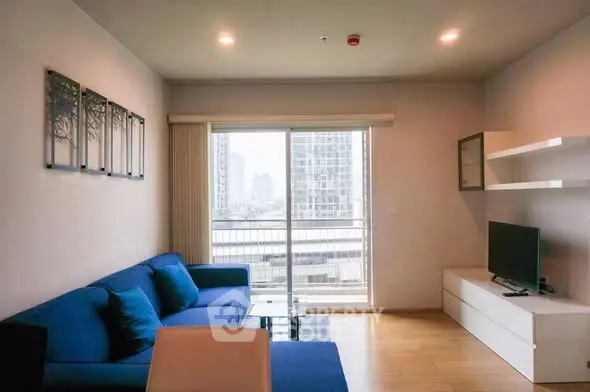 Modern living room with blue sofa and city view balcony in high-rise apartment.