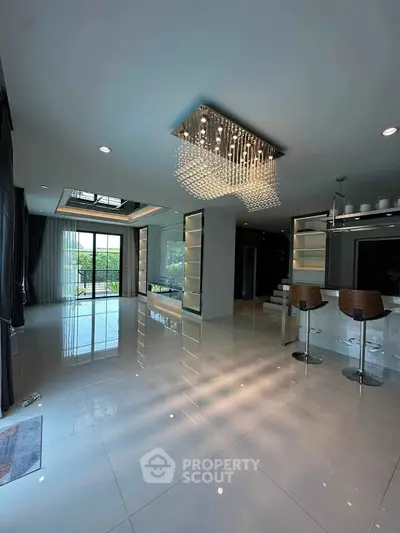 Spacious modern living room with elegant chandelier and open kitchen layout