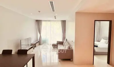 Spacious modern living room with natural light and adjacent bedroom in a stylish apartment.