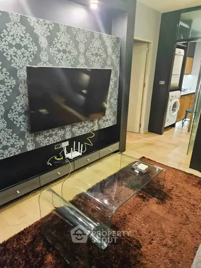 Modern living room with stylish wallpaper, flat-screen TV, and glass coffee table in a cozy apartment.