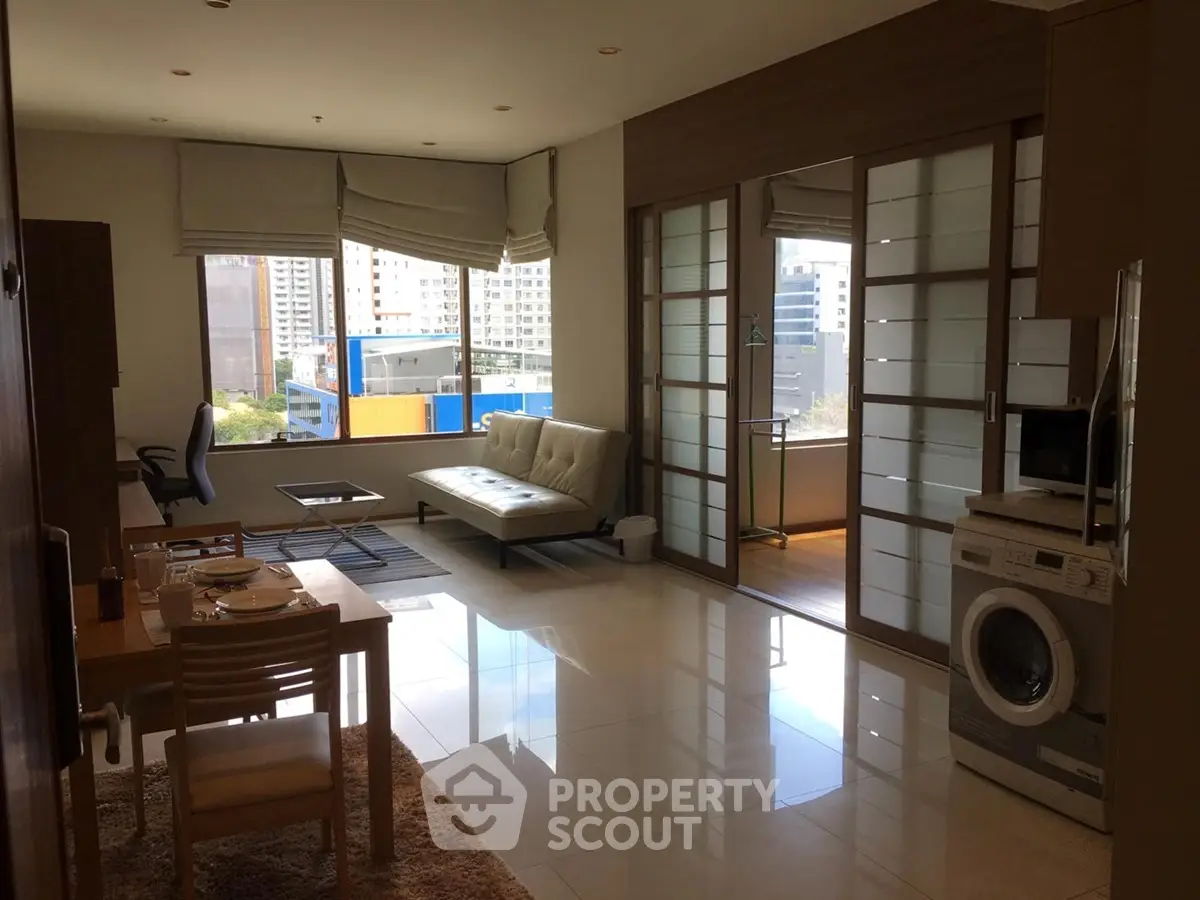 Modern living room with dining area and washing machine, featuring large windows and city view.