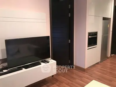 Modern living room with sleek TV setup and integrated kitchen appliances.