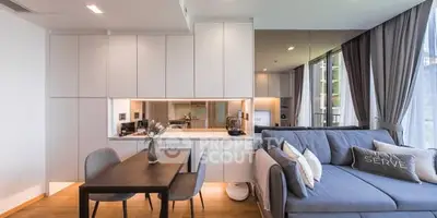 Modern open-plan living room with sleek kitchen and cozy dining area, featuring stylish decor and ample natural light.