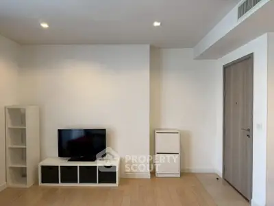 Modern minimalist living room with TV and storage units, featuring sleek wooden flooring and recessed lighting.