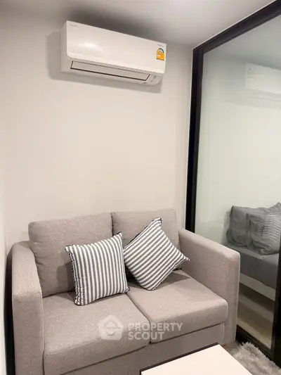 Modern living room with cozy gray sofa and air conditioning unit, perfect for comfortable living.
