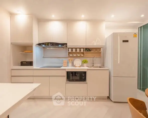 Modern kitchen with sleek white cabinetry and appliances, featuring a spacious fridge and stylish open shelving.