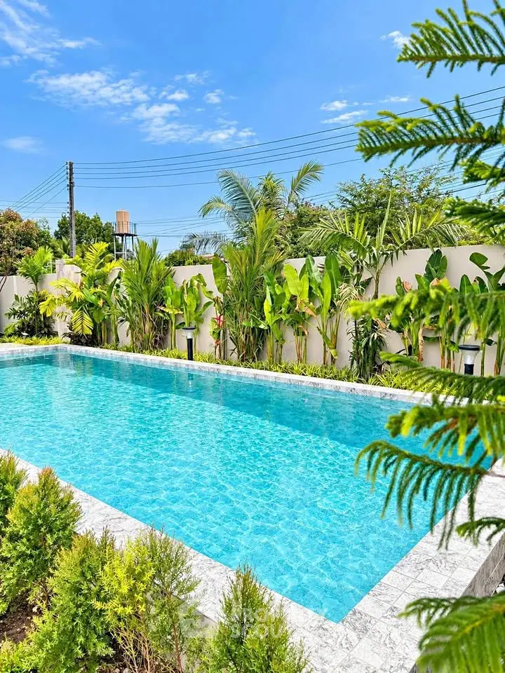 Luxurious outdoor pool surrounded by lush greenery in a serene setting.