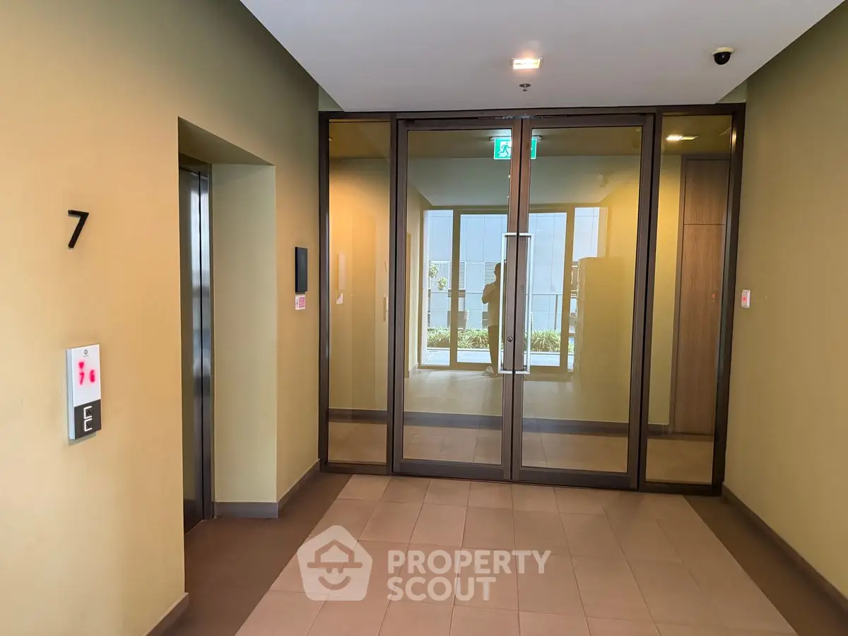 Modern apartment building elevator lobby with glass doors and sleek design.