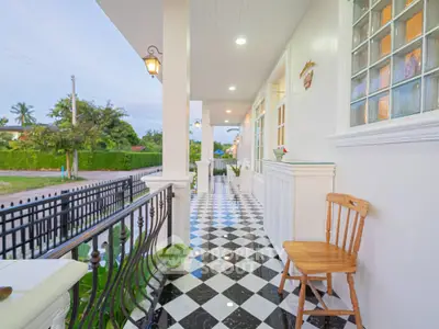 Charming front porch with checkered tiles and cozy seating, perfect for relaxing evenings.