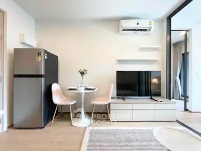 Modern living room with sleek furniture and open layout, featuring a TV and dining area.