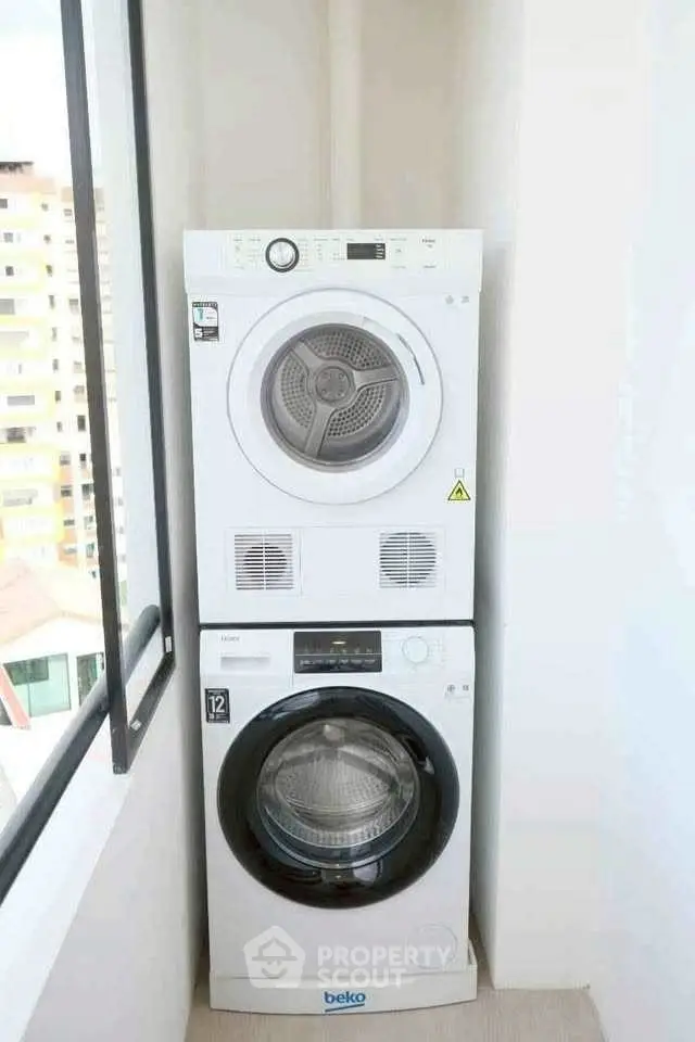 Compact laundry area with stacked washer and dryer in a bright corner space.