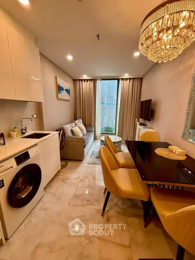 Modern living room with washing machine and elegant chandelier in a cozy apartment.