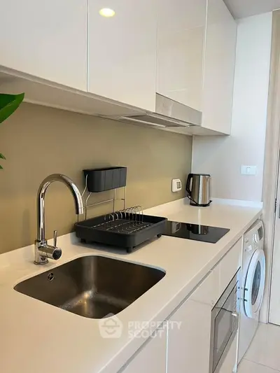 Modern kitchen with sleek white cabinets, built-in appliances, and elegant fixtures.